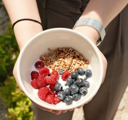a person holding a bowl of cereal and berries