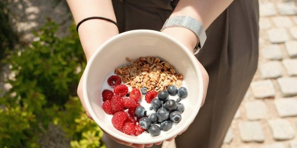 a person holding a bowl of cereal and berries
